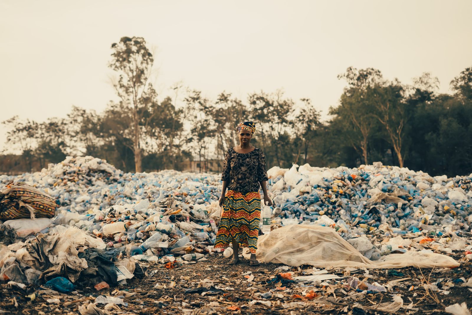 A woman of EcoTribe's plastic collective standing amid the plastic waste she helps recover